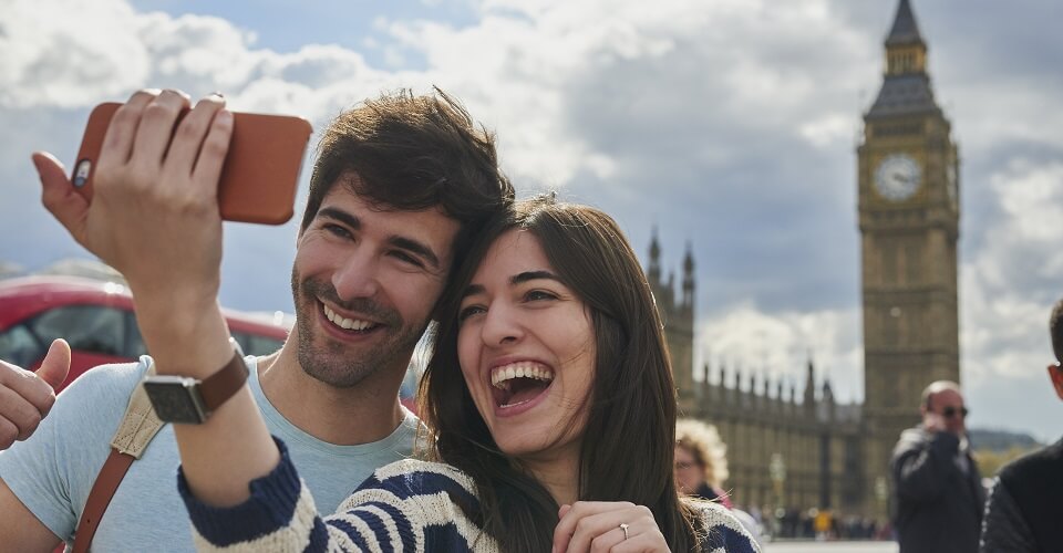 Tourist couple taking selfies smart phone Big Ben London Landmark having fun on adventure travel